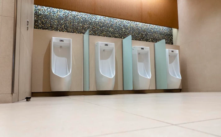 A row of urinals in tiled wall in a public restroom empty man toilet
